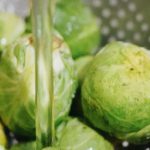 Frischer Rosenkohl wird in einem Sieb gewaschen