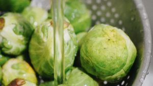 Frischer Rosenkohl wird in einem Sieb gewaschen